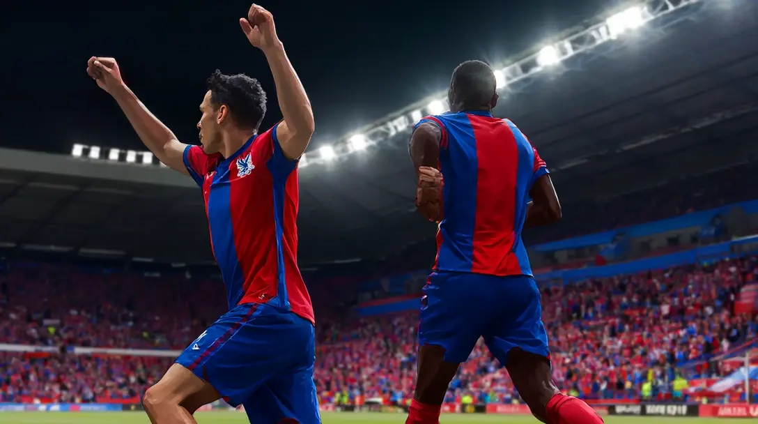 Two Crystal Palace players in red-and-blue striped shirts celebrate a goal under floodlights, one with a raised fist.